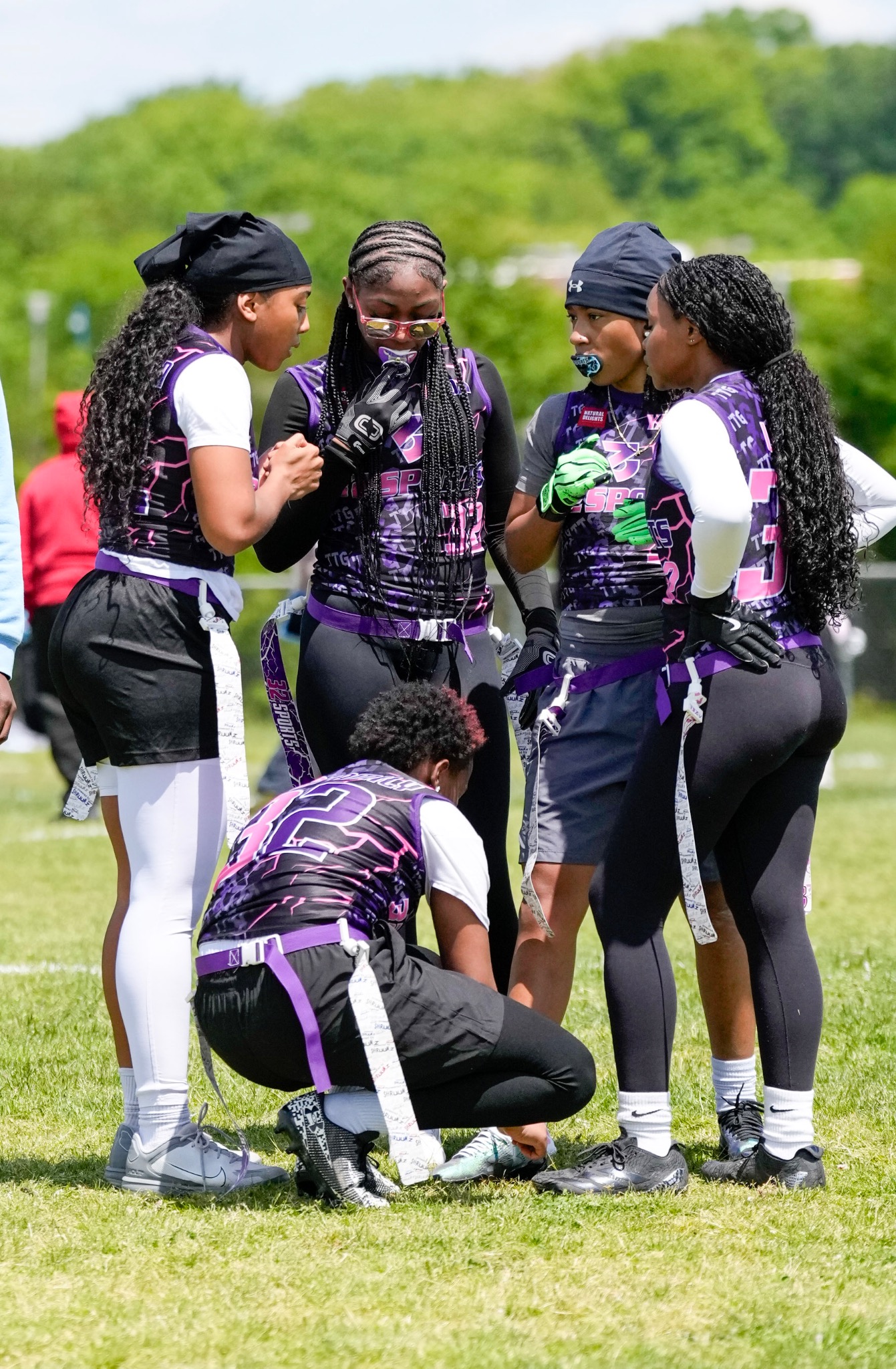 32 Sports girls flag football teammates together in a huddle