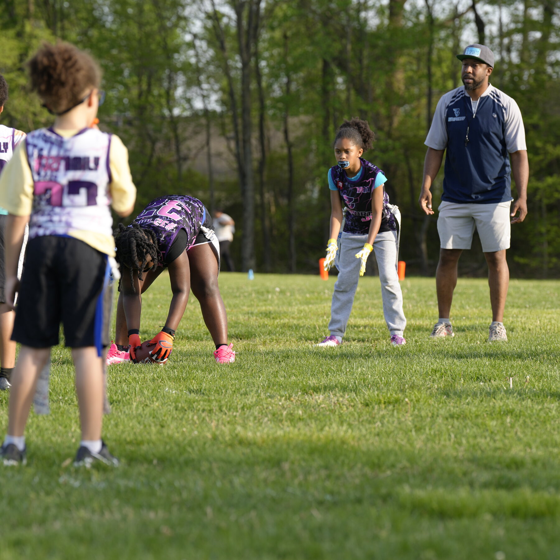 A 32 Sports coach guiding girls during flag football practice